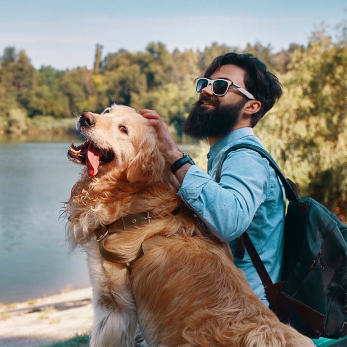 Young man sitting with his dog on the chair in the park